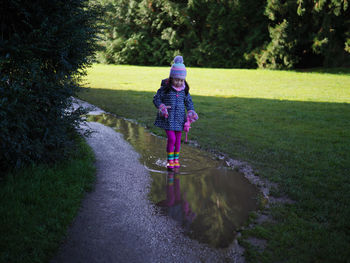 Rear view of  young girl  walking on road during rainy season