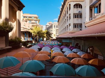 Multi colored umbrellas on street amidst buildings in city