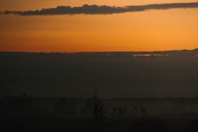 Scenic view of silhouette landscape against orange sky