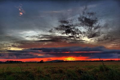 Scenic view of dramatic sky over field during sunset