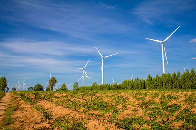 Wind turbines on field against sky