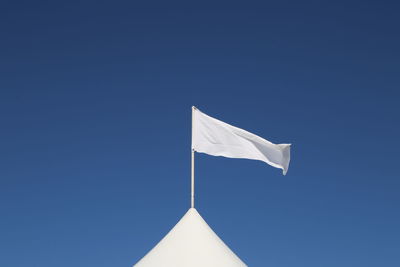 Low angle view of flag against clear blue sky