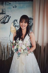 Portrait of happy woman standing against wall