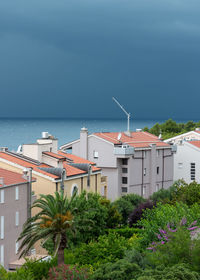 Buildings by sea against sky