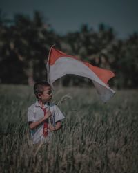 Boy holding umbrella on field