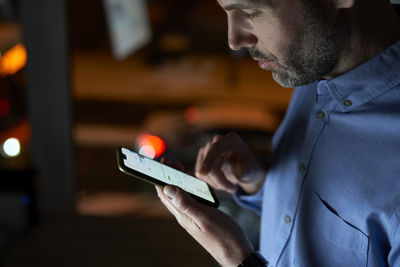 Midsection of man using phone in dark