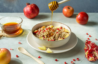 Sweet homemade barley porridge with pomegranate seeds, apples and honey. rosh hashanah celebration