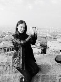 Portrait of young woman standing against cityscape in background