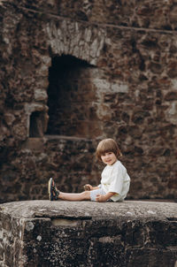 Side view of boy sitting on wall