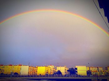 Low angle view of rainbow over buildings in city