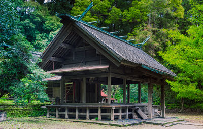 View of shinto shrine among trees in rural forest.