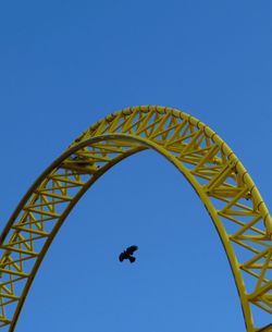 Low angle view of ferris wheel against clear blue sky