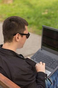 Close-up of man using laptop while sitting outdoors