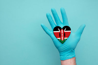 Close-up of hand holding blue over white background