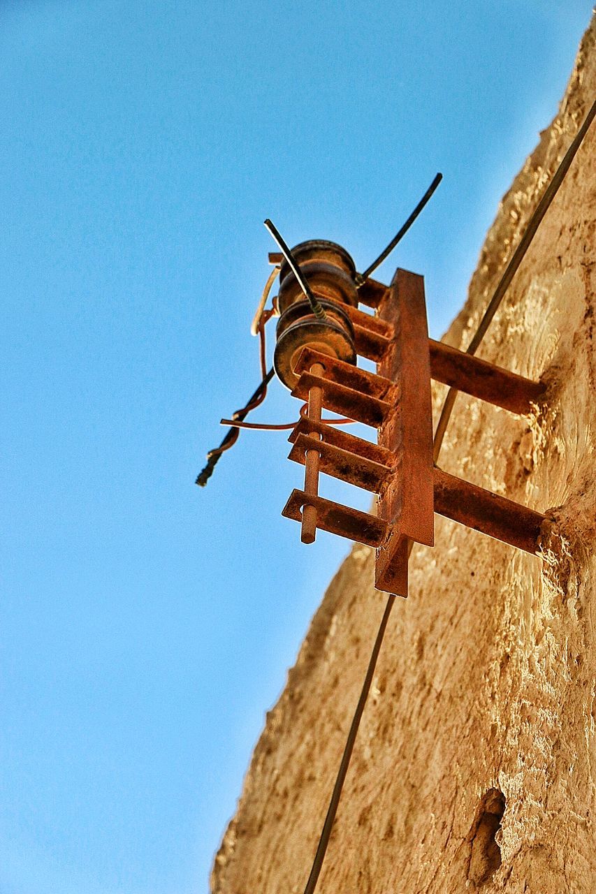 clear sky, blue, low angle view, religion, sunlight, wood - material, spirituality, copy space, day, outdoors, built structure, art and craft, place of worship, history, no people, art, temple - building, architecture, old, human representation