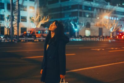 Woman standing on city street at night