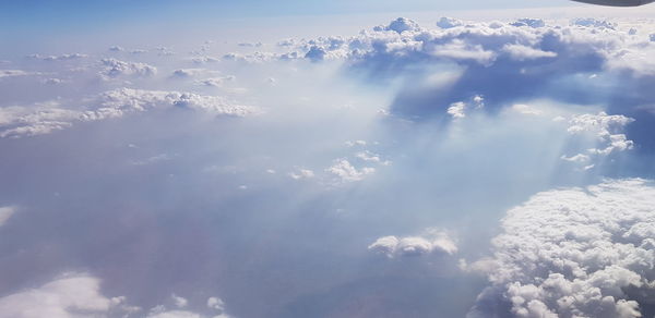 Low angle view of sunlight streaming through clouds