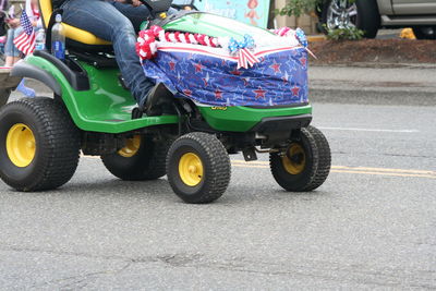 Low section of men riding tractor at street on fourth of july independence day parade