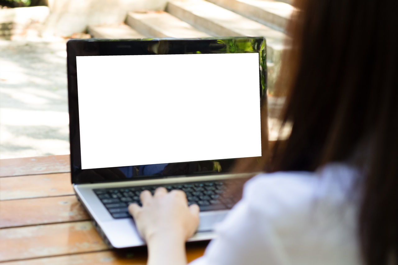 REAR VIEW OF MAN USING LAPTOP