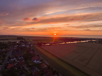 Aerial view of city by sea against sky during sunset