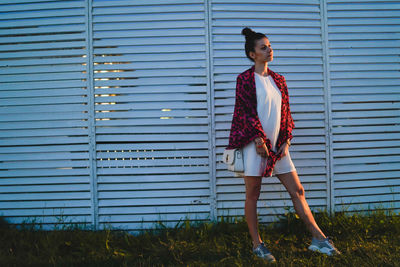 Young woman standing against wall