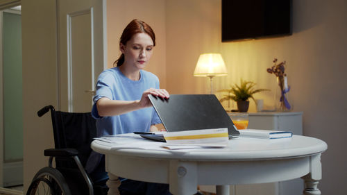 Young woman closing laptop at home