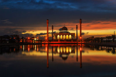 Scenic view of lake and buildings against sky during sunset