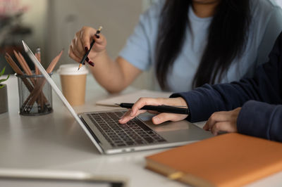 Midsection of woman using laptop at office