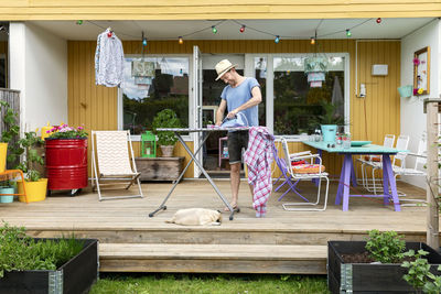 Man ironing clothes on patio