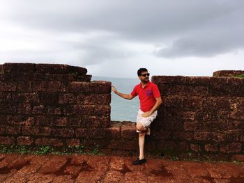 Man standing on retaining wall against sky