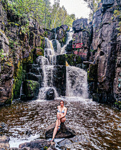 Full length of young woman splashing water in rock