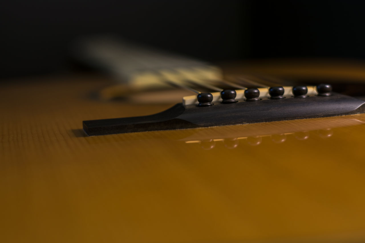 CLOSE-UP OF GUITAR ON TABLE AGAINST WALL