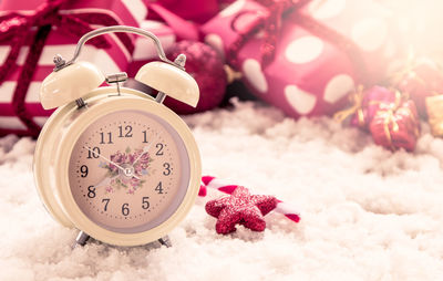 Close-up of clock with christmas presents on snow