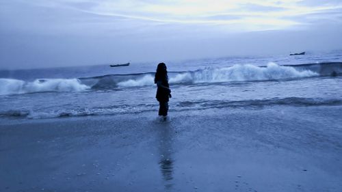 Rear view of man on beach against sky