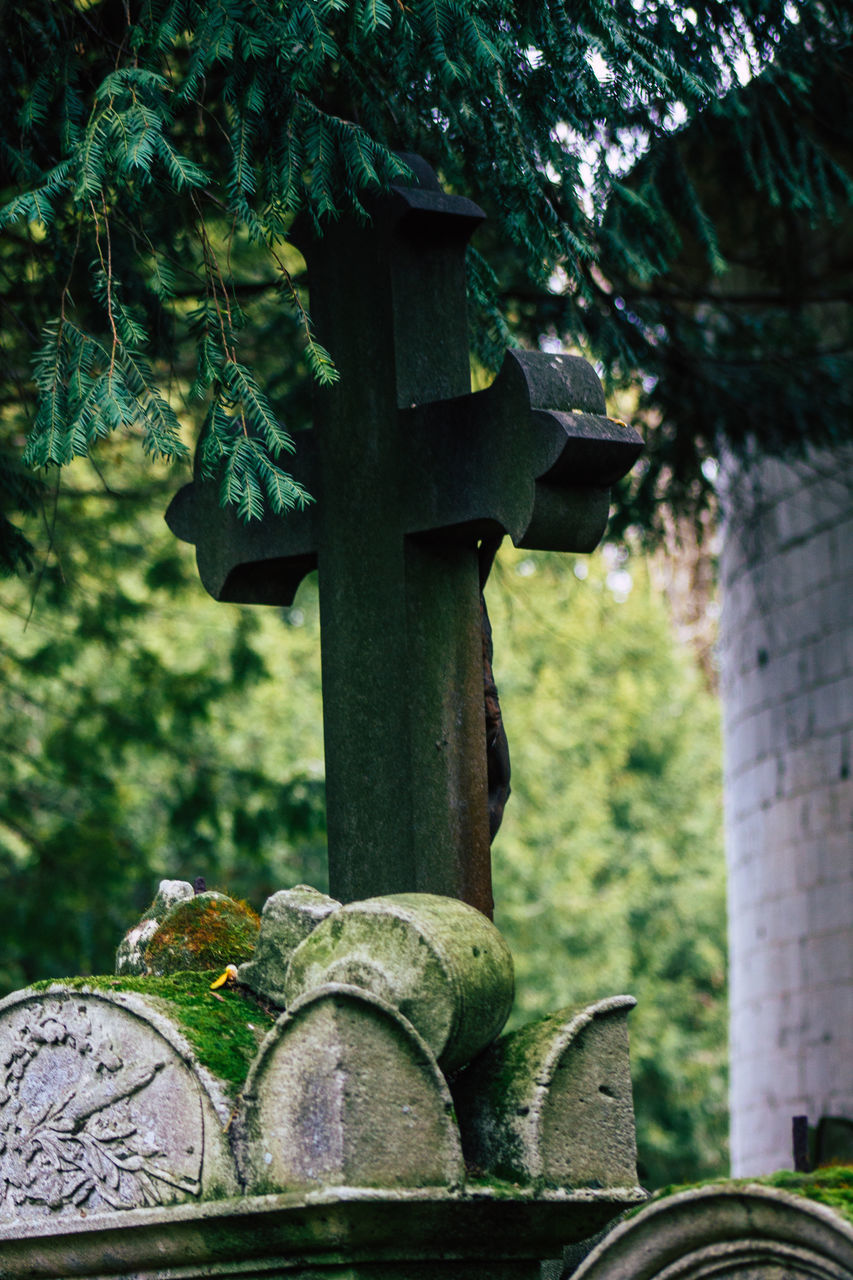 CLOSE-UP OF STONE CROSS AGAINST TREES