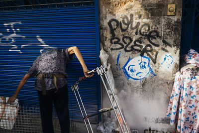 Rear view of woman standing against graffiti wall