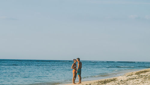 Woman standing on beach against clear sky