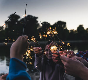 Midsection of woman holding sparkler against sky