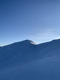 Scenic view of snow covered mountains against clear blue sky