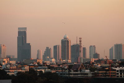 Buildings in city against sky during sunset