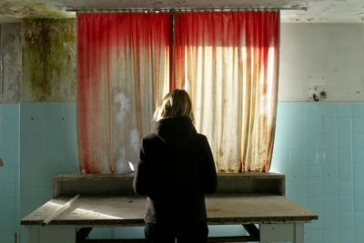 Rear view of woman standing against curtain