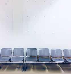 Chairs at waiting area against white wall