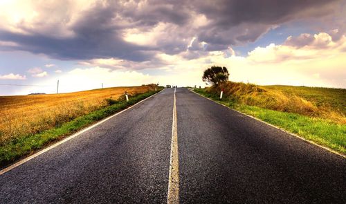 Road amidst field against sky