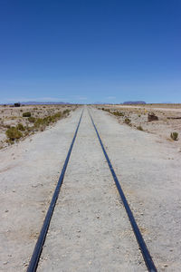 View of railroad tracks against clear blue sky