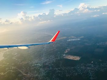 Airplane flying over cityscape against sky