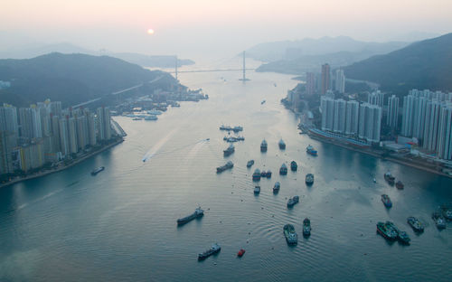 Ships at harbor amidst buildings during foggy weather at morning
