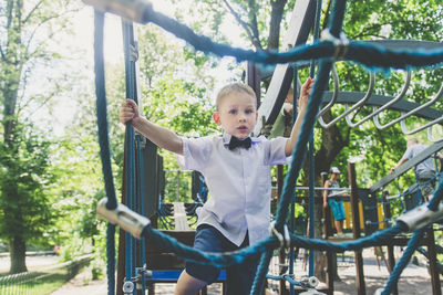 Portrait of boy climbing on rope at playground