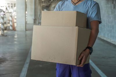 Midsection of man holding paper while standing against wall