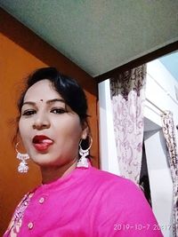 Portrait of woman standing against pink wall