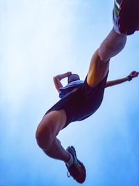 Low angle view of man jumping against sky